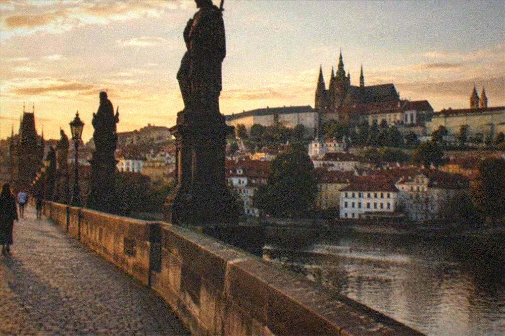 Puente de Carlos en Praga con estatuas a lo largo del pretil y el castillo elevándose en la colina sobre el río