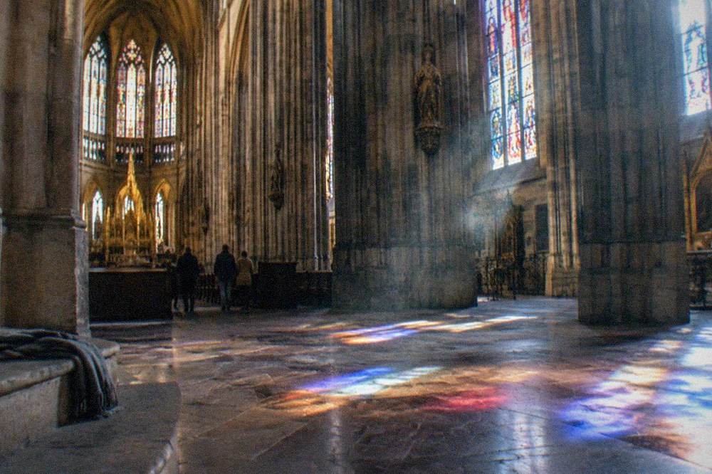 Stained glass windows glowing inside a gothic cathedral nave