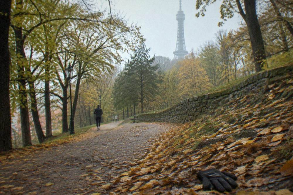 Sendero arbolado en la colina de Petřín con la torre mirador de celosía elevándose sobre el parque