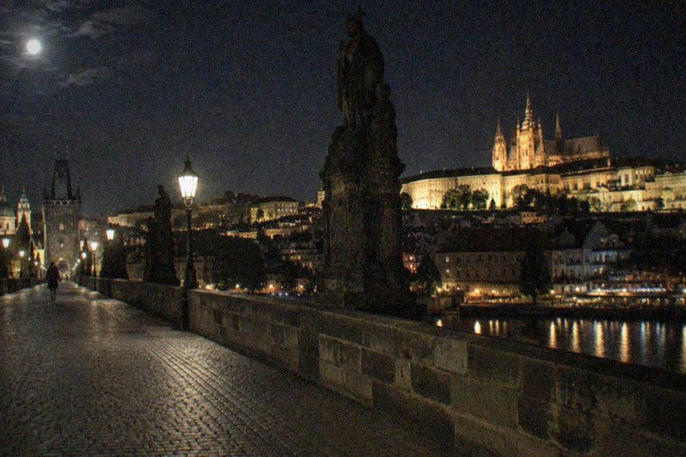 Puente de Carlos y el río Moldava de noche con la colina del castillo al fondo