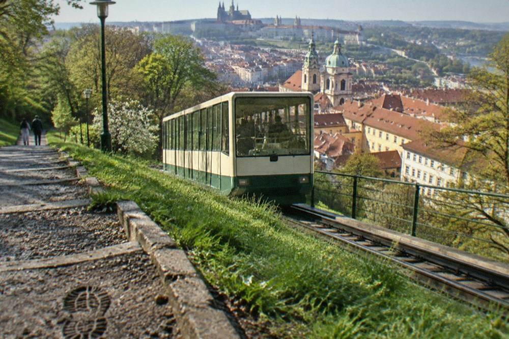 The Petřín funicular cars on the track climbing a green hillside above rooftops