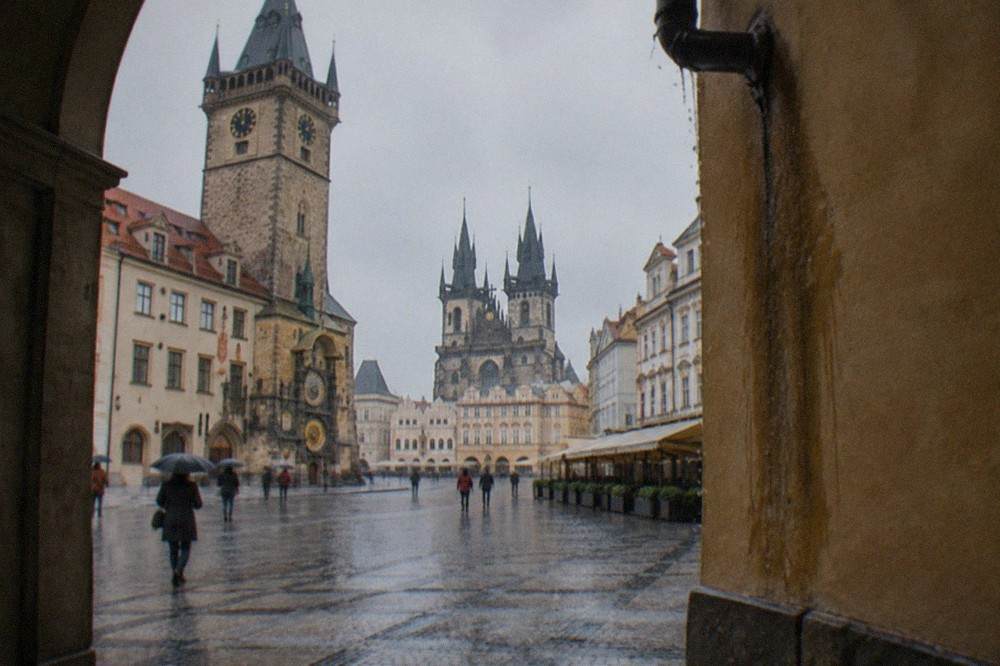 Amplia plaza empedrada de Praga con fachadas históricas y una torre alta con la esfera de un reloj astronómico