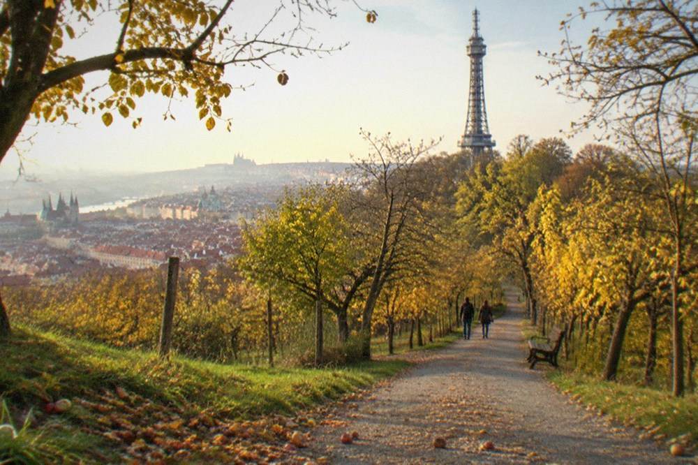 Parque público en terrazas sobre una colina de Praga con una torre de observación de celosía ornamentada y senderos arbolados