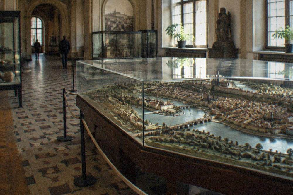 Interior de galería de museo con vitrinas de exposición y suelo de baldosas con patrones