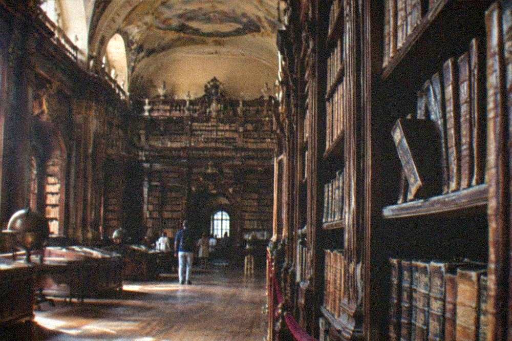 Salón histórico de biblioteca con estanterías de madera altas y techo decorado