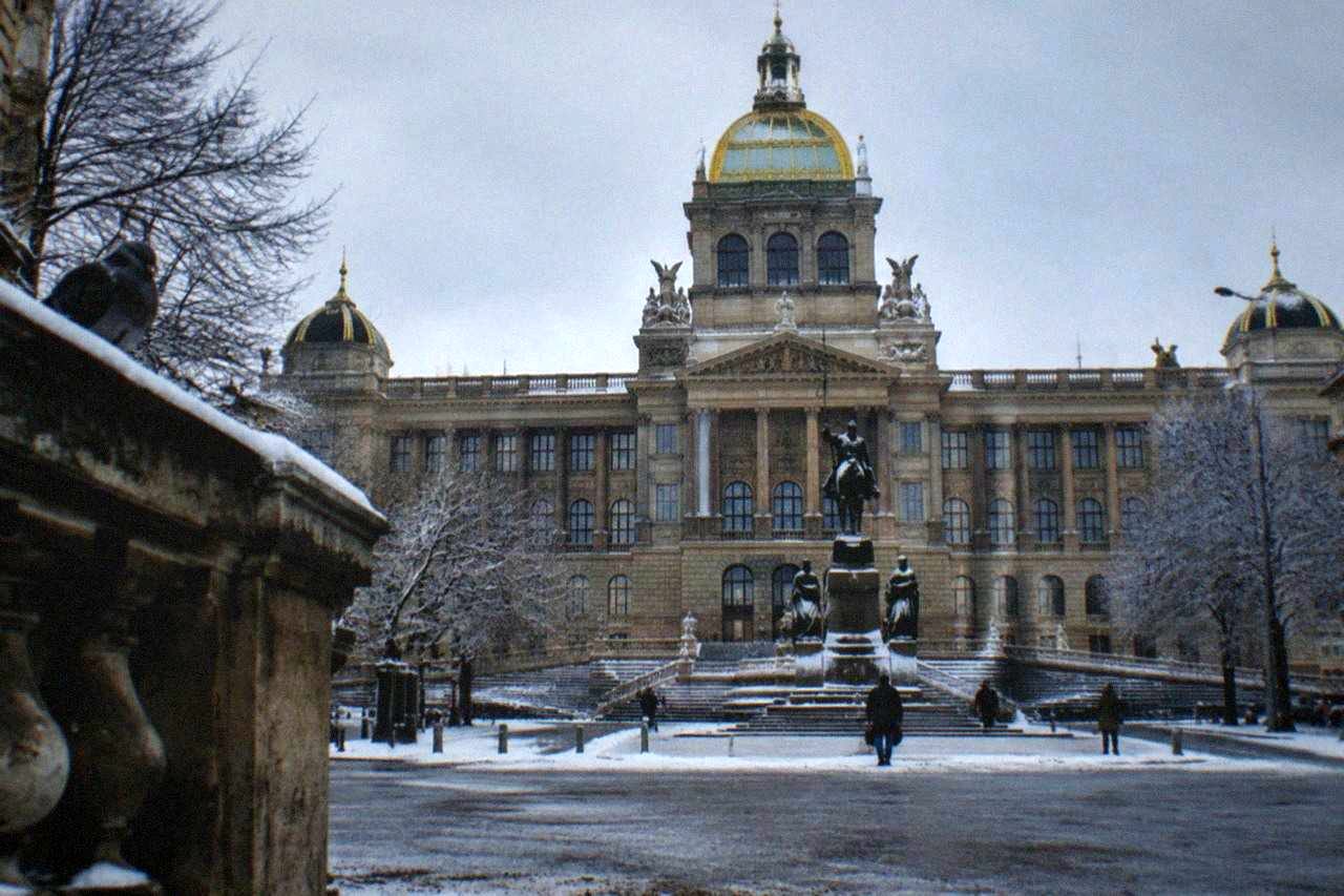 Museum building facade on a Prague street with ornate sculptures under a daytime sky