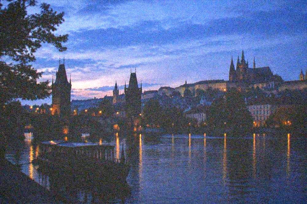 Charles Bridge towers at dusk with the castle silhouette behind them