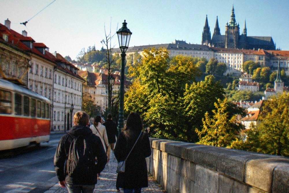 Un grupo de participantes con un guía en la salida de metro cerca de un parque junto al río en Praga