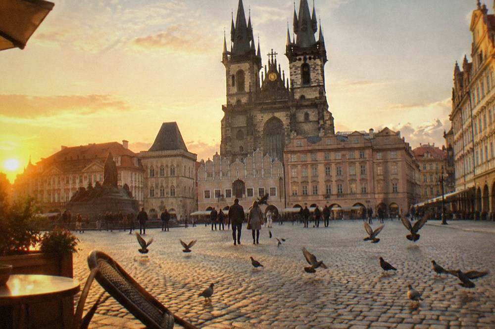 Gothic twin towers of Týn Church rising above the baroque facades of Old Town Square at dusk