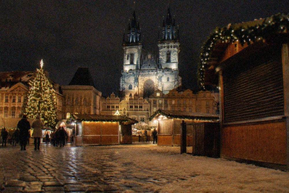 Market stalls lined up across Old Town Square with the towers of Týn Church behind them