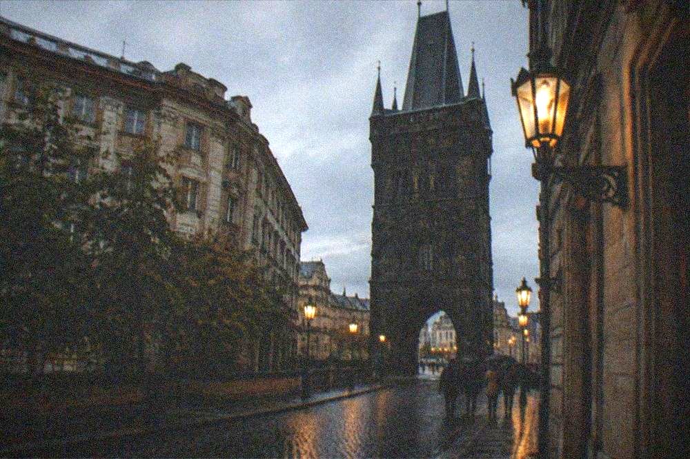 A local guide addressing a gathered walking tour group beside the Powder Tower in Prague