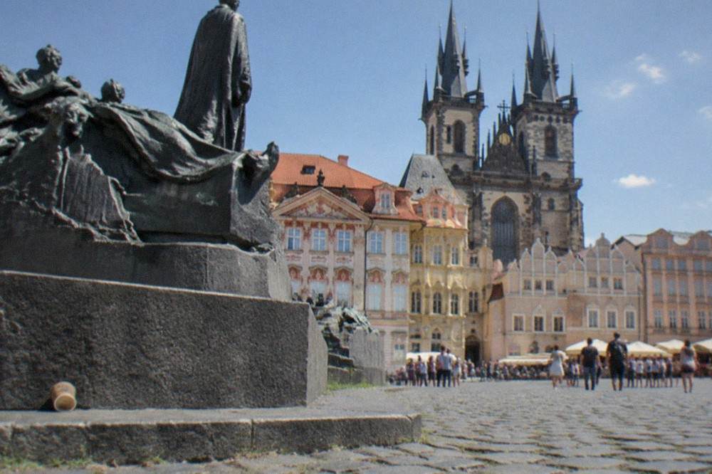 Old Town Square on a summer morning with the Jan Hus monument and colourful baroque facades in bright sunlight