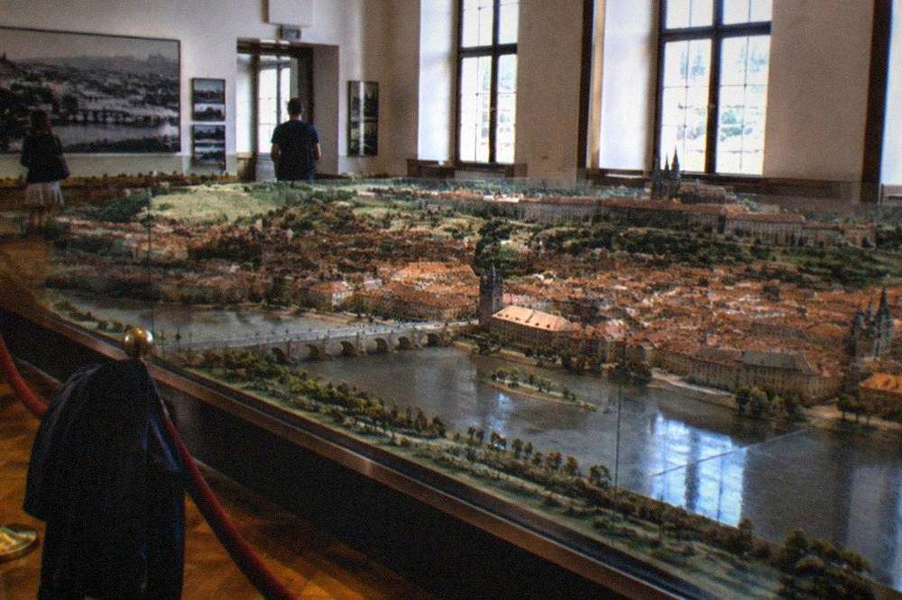 Museum hall with a large historic scale model of a city under glass, lit by tall windows