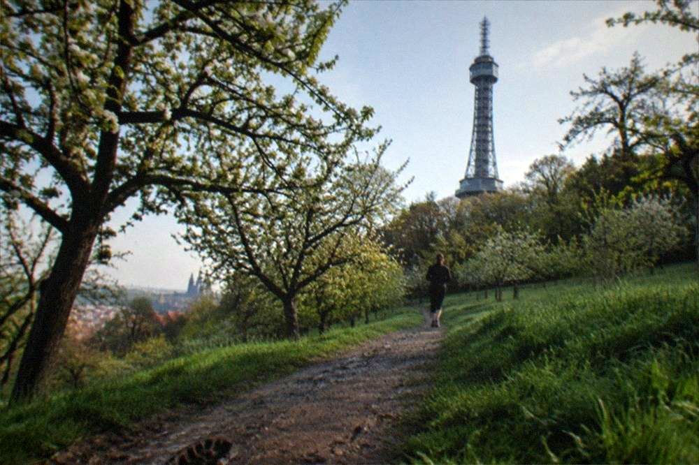Senderos entre huertos que suben por la colina de Petřín con la torre mirador sobre los árboles