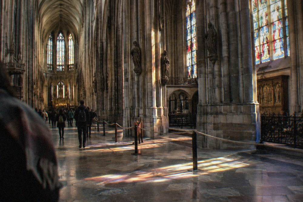 Interior nave of a Gothic cathedral with stone pillars and stained glass windows